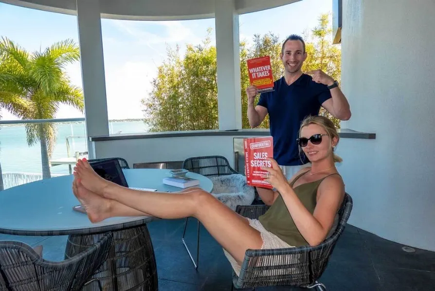 A woman lounging and holding the Sales Secrets book. A smiling man stand behind her holding and pointing to his Whatever It Takes book.